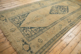 Angled view of the antique Kurdish runner, highlighting its distressed texture and geometric pattern.