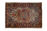 Antique Farahan Sarouk rug with a large floral medallion in sapphire blue and rust on an ivory field.