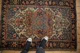 A top-down view of the antique Farahan Sarouk rug, showing its full medallion design and scale on a wood floor.