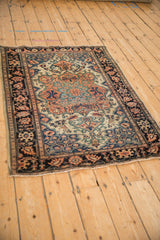Angled view of an antique Farahan Sarouk rug highlighting its large scale medallion and complex border.
