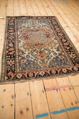 Angled perspective of an antique Farahan Sarouk rug's ivory field and dark navy meandering vine border.