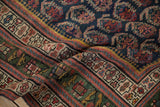 Close-up of the antique Northwest Persian rug's deep green main border and contrasting geometric guard patterns.