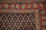 Corner detail of an antique Bijar rug showing its navy lattice field and red meandering vine border.