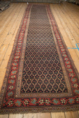 Angled perspective of a long antique Bijar runner showing its panel lattice field and red border.