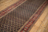 Angled view of an antique Bijar runner's navy blue lattice field and red floral border.