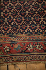 Close view of an antique Bijar runner's navy lattice field and meandering vine border.