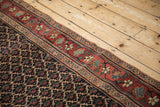 Madder red border with floral motifs next to the navy lattice field of an antique Bijar runner.
