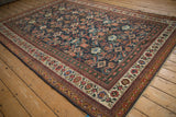 Angled view of an antique Mahal carpet showcasing its complex, colorful Herati-style pattern.