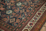 Vivid geometric Herati motifs on the navy field beside the floral border of an antique Persian Mahal carpet.
