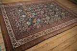 Angled view of the antique Mahal carpet's corner, showing the floral borders and geometric navy Herati field.