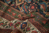 Richly textured pile of a folded antique Mahal showing vivid red, blue, and green geometric Herati motifs.