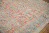 Distressed vintage Tabriz carpet detail showing faded red, blue, and beige vinery and border.