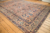 Curvilinear navy arabesque border and dusty coral field on antique Kerman carpet.