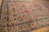 Antique Kerman carpet detail: dusty coral field, navy arabesques, and serrated palmettes.
