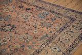 Detail of antique Kerman carpet: scrolling arabesques and sharp palmettes on dusty rose with navy blue border.