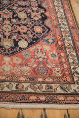 Antique Malayer rug runner corner showing navy Herati field and layered borders in blush and beige.