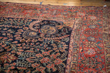 Intricate red and blue floral vinery on the dark navy field of a vintage Sarouk rug.