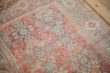 Angled view of the vintage Bijar's dusty teal samovar turtle border next to the ruby red Herati field.