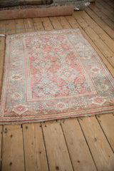 Angled view of a distressed Bijar rug with ruby and dusty teal Herati pattern.