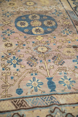 Distressed vintage Khotan rug detail with mauve field, cobalt roundel, and saffron geometric vines.