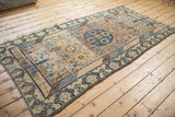 Distressed vintage Khotan runner with blue geometric vines and patterned brown border.