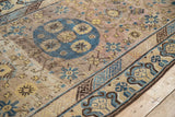 Distressed Khotan rug section revealing worn foundation, with mauvy, blue, and saffron geometric patterns.