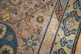 Distressed Khotan rug runner shows worn mauve field, geometric vines, saffron and cobalt blue buds.
