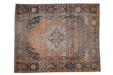 Antique Persian Mohtashem Kashan carpet with a faded rust floral field, central medallion, and dark navy border.