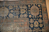 Faded rust floral border and dark navy spandrel on an antique hand-knotted Mohtashem Kashan carpet.