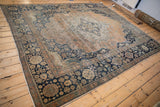 Full perspective of an antique Mohtashem Kashan carpet with a faded rust medallion and navy floral border.