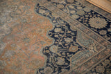 Visible knot heads and floral motifs on the faded rust field and navy border of an antique Persian rug.