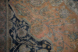 The textured, low pile of an antique Mohtashem Kashan with faded rust and deep navy floral vinery.