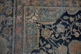 Corner view of a worn antique Kashan showing jade green spandrels and a faded rust floral border.