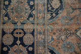 Wear to the foundation on an antique Mohtashem Kashan's navy, rust, and jade floral patterns.