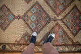 Detail of an antique Persian rug showing even wear across the interconnected diamond medallions.