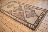 Angled view of an antique Northwest Persian rug showing its full unidirectional pattern and medallions.