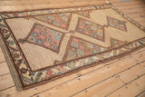 An antique Northwest Persian rug's full length shown from an angle, highlighting its triple medallions.