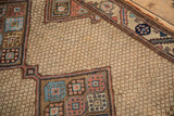 Detail of the antique rug's beige lattice field and the medallion's geometric gul motifs.