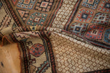 A fold in an antique Persian rug reveals the detailed lattice field and rich floral blossom border.