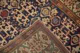 Contrasting navy blue and jade green geometric patterns on an antique Caucasian rug.