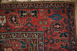 Antique Northwest Persian rug corner with ruby red floral field and navy vine boteh border.