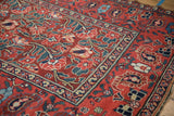 Antique Northwest Persian rug detail: cherry red abrashed field, sprawling florals, navy boteh border.