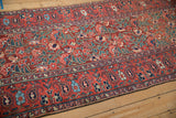 Antique Northwest Persian runner's abrashed cherry red field, sprawling floral motifs, paisley border.