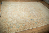 Angled view of a vintage Heriz carpet highlighting its distressed, low-pile texture and geometric pattern.