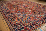 Angled view of a vintage Heriz carpet with sprawling geometric vines and blossoms.