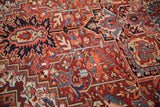 Detail of a vintage Heriz rug's geometric vines, with highlights of tangerine orange and dusty teal.