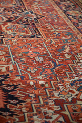 Detailed view of the brick red and navy blue geometric motifs on a vintage Heriz carpet.