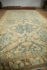 Perspective view of a distressed Kurdish carpet with geometric medallions in dusty blue and sand tones.