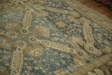 The storied low pile of a distressed Kurdish rug with Seichor Caucasian designs in dusty blue and sand.