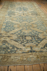 Low angle view down the length of a distressed Kurdish rug showing its sprawling blue medallions.